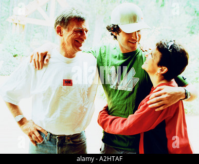 Lifestyle Image of mum,dad and there son age 20-25. They are all hugging each other. Stock Photo