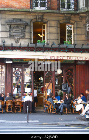 Le Bistrot du Peintre cafe bar terrasse terrase outside seating on the sidewalk. People sitting in chairs at tables eating and drinking outside at lunch time. The Bistrot du Peintre is an old fashioned Paris café cafe bar restaurant of art nouveau design with polished brass, mirrors and old signs Stock Photo