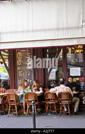 Le Bistrot du Peintre cafe bar terrase outside seating on the sidewalk. Two young women having a drink and chatting on a wicker Stock Photo