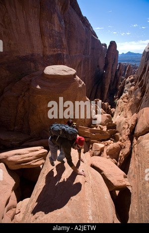 Hiker scrambling up vertical rock wall. Free solo up rock climb in ...