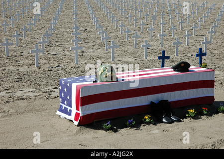 A military coffin draped in the stars and stripes flag in front of a sea of white crosses on Santa Monica beach, Los Angeles, CA Stock Photo