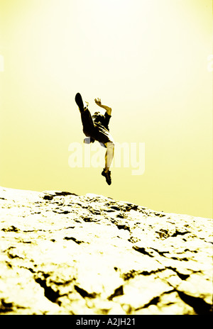male age 20-25 jumping off a rock. The Image is shot from below. Stock Photo