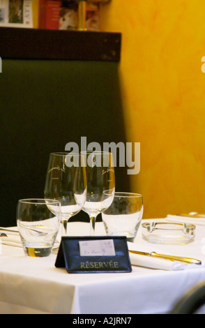 A restaurant table with a sign saying Reserve Réservé showing that the table is reserved booked. White linen table cloth, wine glasses. At the restaurant Le Gourmandin. in Beaune Cote d'Or Burgundy Bourgogne France Europe Stock Photo