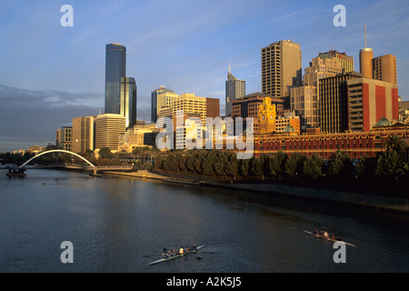 Australia, Melbourne. Crew teams on Yarra River by Flinders Street Railway Station and skyline. Stock Photo