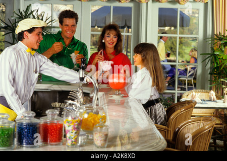 Young family having fun at restaurant ice cream counter together Stock Photo