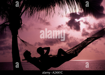 Silhouette of romantic couple on holiday in hammock relaxing in Caribbean Mexico on beach Stock Photo