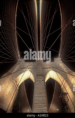 The feathery cables of the Brooklyn Bridge in New York City are show illuminated at night and photographed with a fish eye lens Stock Photo