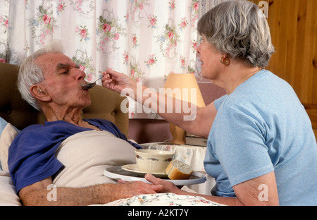 mature woman spoon feeding soup to sick elderly man Stock Photo