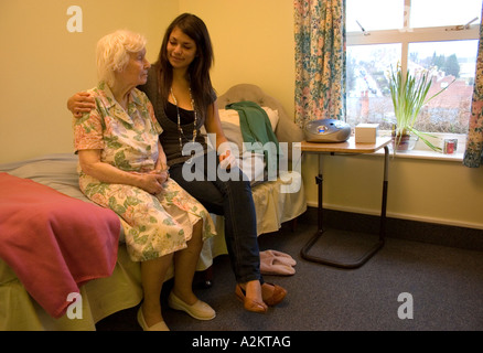 young woman/teenager /care worker visiting very old lady/her grandmother in nursing home Stock Photo