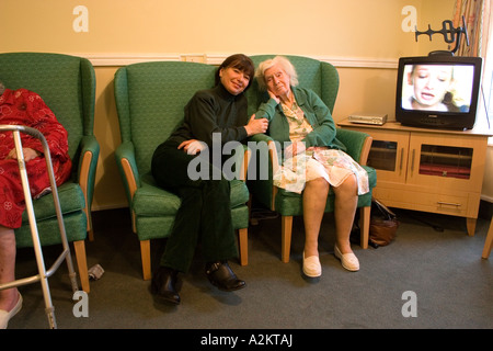 portrait middle aged woman/daughter/care worker visiting very old lady/her mother in nursing home Stock Photo