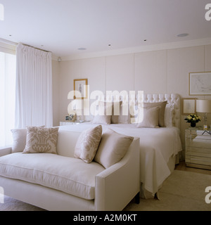 Plush bedroom in cream with cushioned headboard and sofa Stock Photo