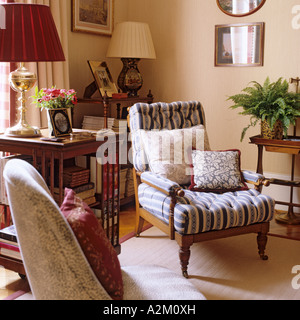 Upholstered armchair with cushions and lamps on shelf table Stock Photo