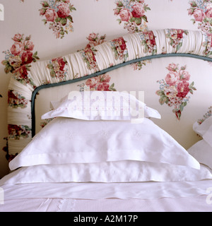 fabric-covered bed head and pillows in crisp white cotton slips Stock Photo