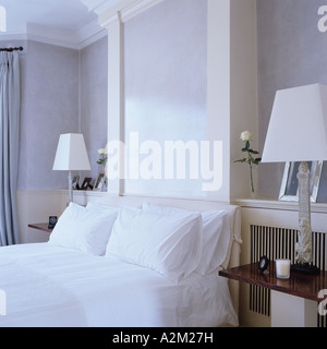 Double bed with white linen and lamps Stock Photo
