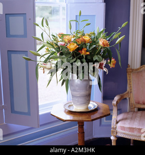 Vase of flowers on octagonal in front of window with shutters Stock Photo
