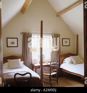 Twin beds in attic room with pitched roof and window Stock Photo