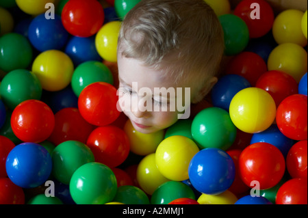 baby sitting in box with hundreds of colorful plastic balls Stock Photo