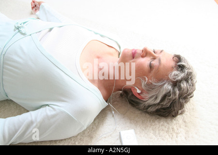 High angle view of senior woman listening to MP3 player Stock Photo