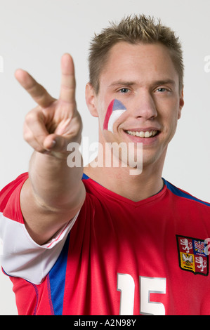Portrait of male soccer fan showing victory sign and smiling Stock Photo