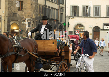 Contrasts meet in Florence, Italy: a mature formally dressed coach driver chats with middle-aged casually dressed man on a bike Stock Photo