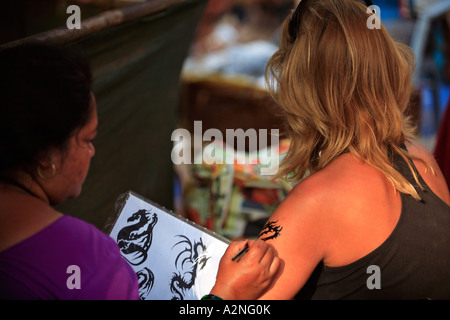 INDIA NORTH GOA ANJUNA WEEKLY MARKET A GIRL HAVING A HENNA TATTOO APPLIED ON HER ARM Stock Photo