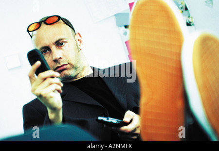 Young man using mobile phone and PDA in office Stock Photo