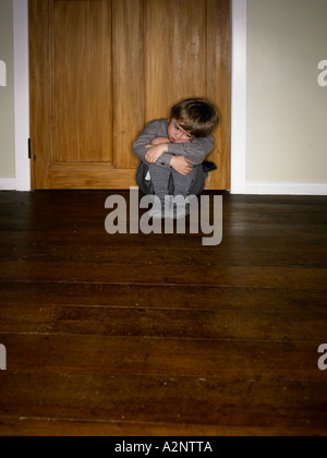 school boy curled up not wanting to go to school and sulking looking vunrably Stock Photo