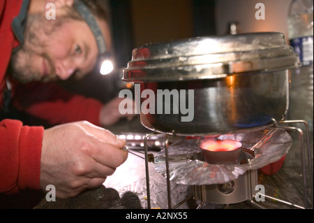 hiker cooks his tea on a camping stove in Camusnary bothy Scotland Stock Photo