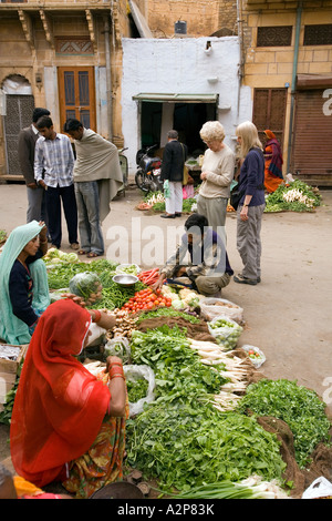 India Rajasthan Jaisalmer Bhatia Market western female tourists looking at vegetable sellers Stock Photo