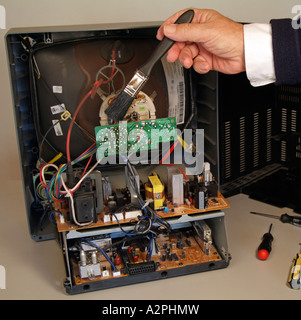 Television set The interior of a tv and video recorder Circuit board The repairmans hand with cleaning brush Stock Photo