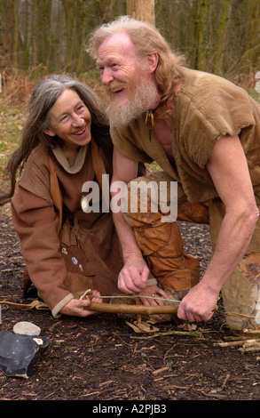 Prehistoric man & woman stone age reenactors trying to make fire at The Museum of Welsh Life St Fagans Cardiff Wales UK Stock Photo