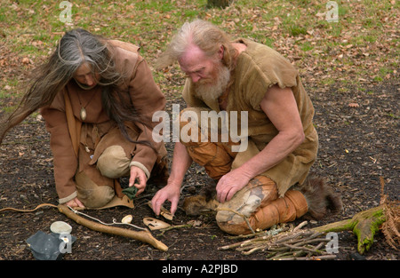 Prehistoric man & woman stone age reenactors trying to make fire at The Museum of Welsh Life St Fagans Cardiff Wales UK Stock Photo