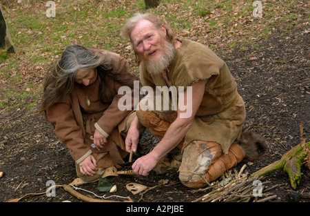 Prehistoric man & woman stone age reenactors trying to make fire at The Museum of Welsh Life St Fagans Cardiff Wales UK Stock Photo