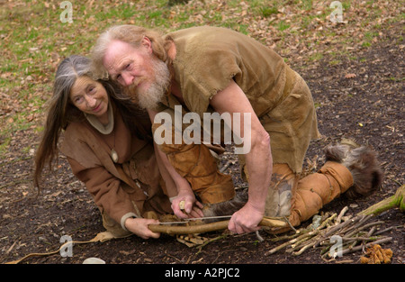 Prehistoric man & woman stone age reenactors trying to make fire at The Museum of Welsh Life St Fagans Cardiff Wales UK Stock Photo