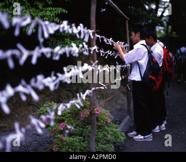 Japanese junior high students attaching fortune papers to string outside Kinkaku ji temple Stock Photo