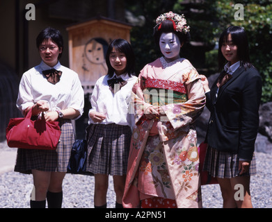 Japanese Junior High School students pose next to Girl in maiko trainee Geisha costume in Japanese garden of Gion Kyoto We Stock Photo
