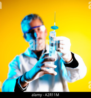 Doctor with Syringe lit by Blue light on Yellow Background Stock Photo