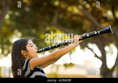 A young girl ten years old plays her clarinet in a park Los Angeles California Model Released Stock Photo