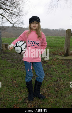 Ten year old girl wearing pink NEXT sweater with football in field UK Stock Photo