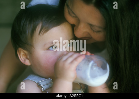 Mixed Asian Caucasian mother hugging mixed Asian Caucasian bottle feeding infant son Stock Photo