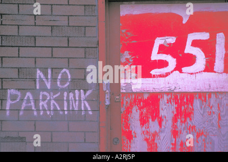 No Parking Sign written on a Brick Wall with Street Address in Red and White Stock Photo