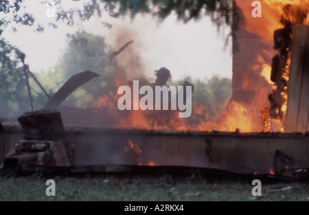 A fire fighter behind the flames of a house burned to the ground Stock Photo