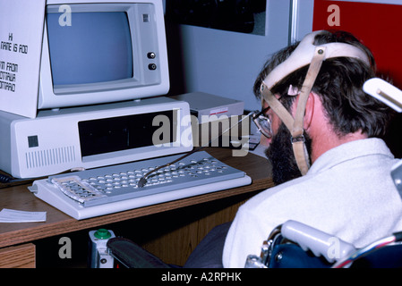 Disabled Man using Computer by typing on Keyboard with a Specially Fitted Head Pointing Device Stock Photo