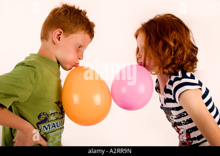 Red haired and freckled twins age7 Blowing up balloons Studio shot Models Released Stock Photo