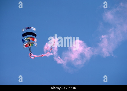Four Sky Divers skydiving and hooking up in Formation and trailing Pink Smoke Stock Photo