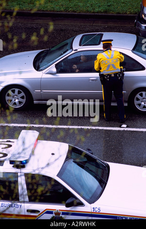 Police Officer writing a Ticket for Traffic Violation Incident to Motorist driving in a Car Stock Photo
