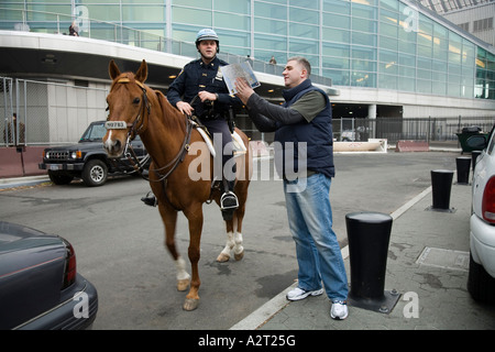 Police Officer gives directions to tourist near Government office South Ferry New York City. USA. Stock Photo