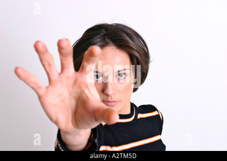 Young, short-haired hispanic woman reaching towards the camera Stock Photo