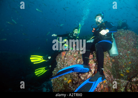 Divers sitting on a rock and waving in Galapagos Underwater Stock Photo