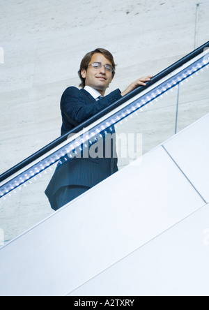 Businessman going up on escalator, portrait Stock Photo
